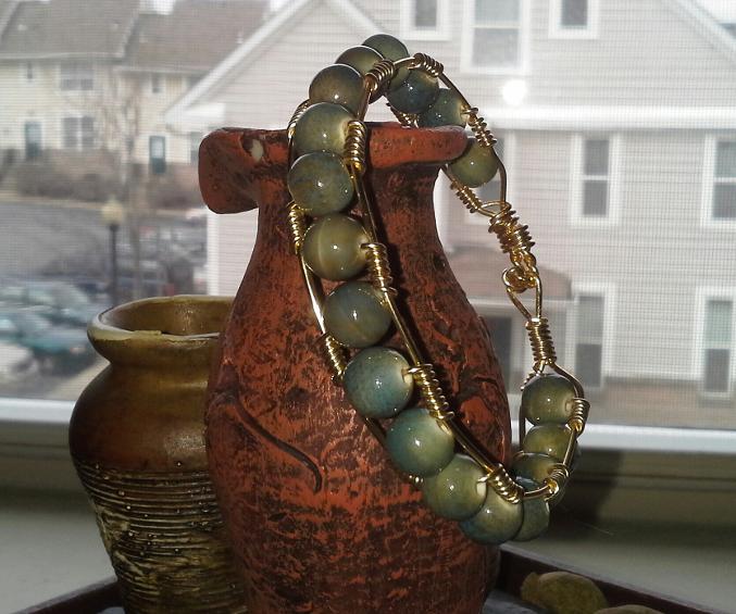 This beautiful handmade wire bangle is a art piece that I'm sure you would love to have in your collection. It's made with marble like, greenish blue clay beads, wrapped with gold 20inch gauge wire. Easy to wear with a t-shirt and jeans. or for an elegant dress or skirt.